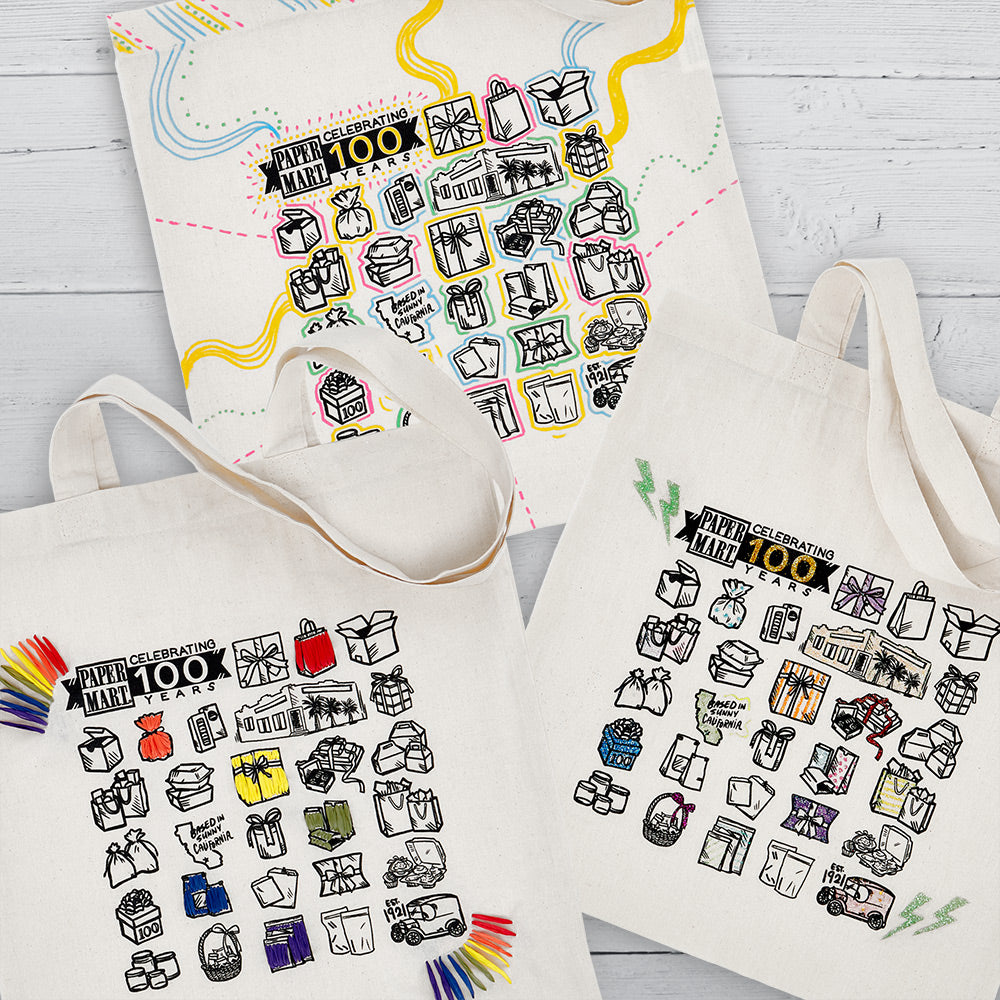 flat lay image of paper mart canvas totes decorated with glitter, markers, and ribbon
