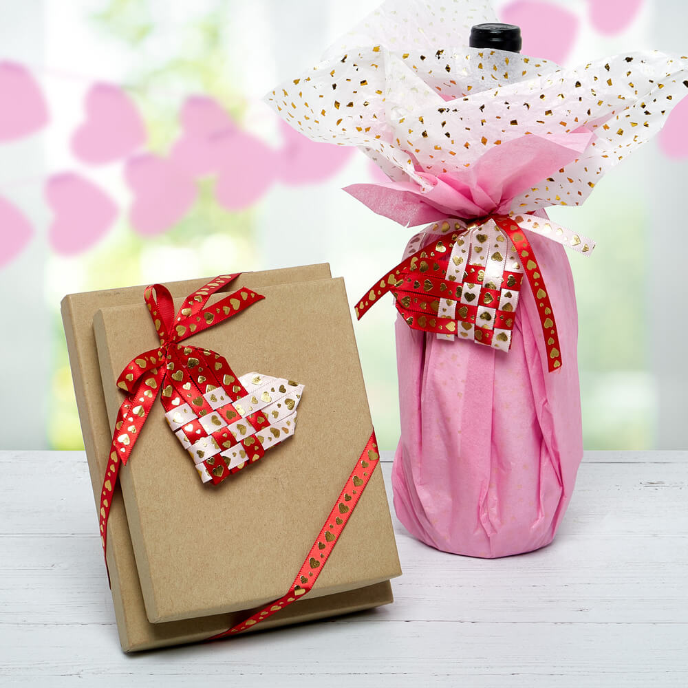 boxes and a bottle wrapped with paper mart ribbon and decorative tissue paper